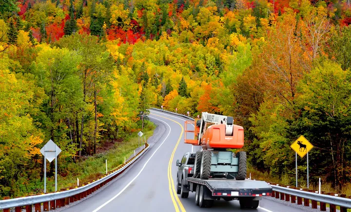 Camion Transport JML transportant de l'équipement lourd sur une route québécoise
